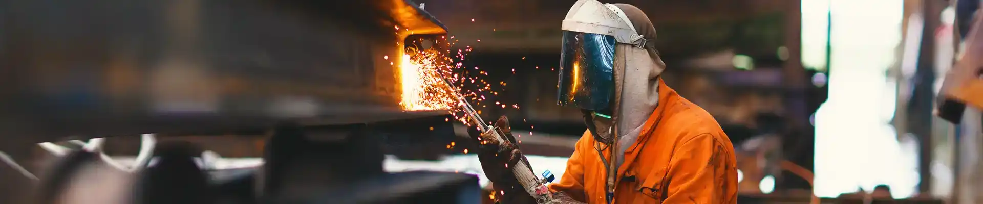 A technician wearing a welding helmet welding.